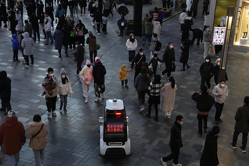 FILE - A police robot vehicle patrols near the crowd that has returned to a mall following the easing of pandemic restrictions in Beijing, Sunday, Jan. 1, 2023. European Union nations are fine-tuning a coordinated response to China's COVID-19 crisis on Wednesday, Jan. 4, 2023 and are zeroing in on travel restrictions that would upset both Beijing and the global airline industry. (AP Photo/Ng Han Guan, File)