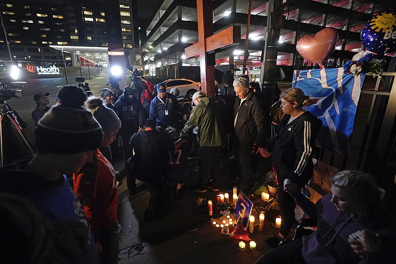Personas asistentes a una vigilia encienden velas y oran por la recuperación de Damar Hamlin, jugador de los Bills de Buffalo, frente al Centro Médico de la Universidad de Cincinnati, el martes 3 de enero de 2023 (AP Foto/Darron Cummings)
