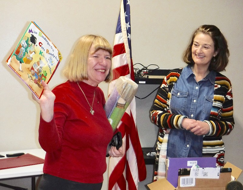 Westside Eagle Observer/SUSAN HOLLAND
Melinda Griffin, right, director of the Sulphur Springs Library, looks on as Gravette Kiwanis Club president Dr. Nancy Jones displays one of the children's books donated to the library by the club. Griffin was speaker for the Friday, Jan. 6, Kiwanis Club meeting, followed by the presentation of books and a rug for the children's room.