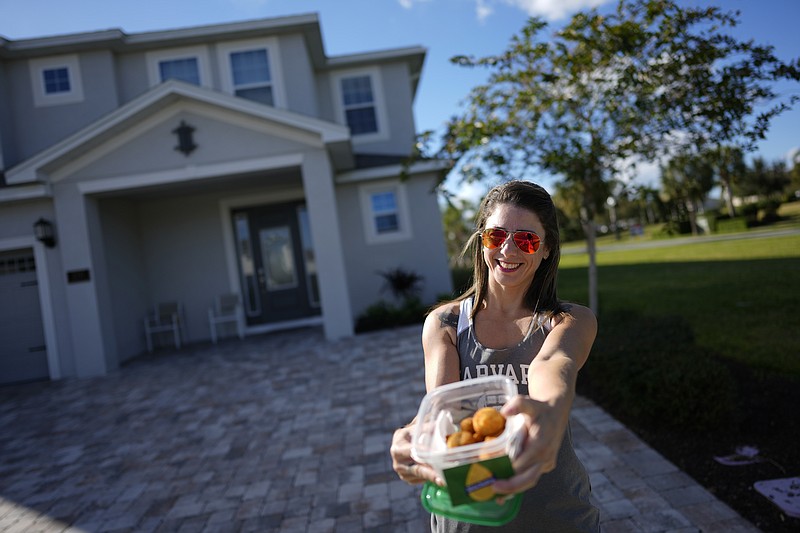 Alessandra Vieira, a Brazilian Cape Canaveral resident who runs a Brazilian food business and was in the area making a delivery, displays the homemade caxinhas she brought to offer former Brazil President Jair Bolsonaro, outside the house where he is staying, Monday, Jan. 9, 2023, in Reunion, Fla. As Brazil reels from mobs of rioters swarming its seats of power, its former leader has decamped to a Florida resort, where droves of supporters have flocked to cheer on their ousted president. (AP Photo/Rebecca Blackwell)