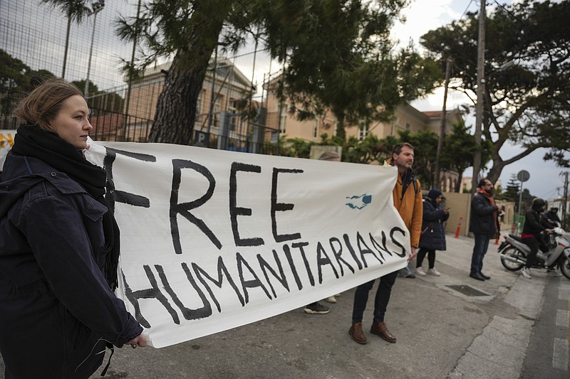 Defensores de los 24 trabajadores humanitarios que están acusados de participar en operativos de rescate de migrantes sostienen un letrero afuera del tribunal de Mitilene, en la isla de Lesbos, Grecia, el martes 10 de enero de 2023. (AP Foto/Panagiotis Balaskas)