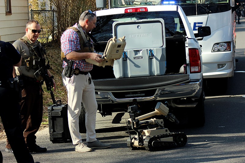 Garland County Sheriff’s Department Investigator Charlie Mowery, right, remotely controls a tactical robot toward a residence in the 400 block of Woodlawn Avenue Tuesday morning while Sgt. John Schroeder follows. - Photo by James Leigh of The Sentinel-Record