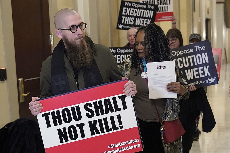 The Rev. Jeffrey Hood of Arkansas, left, and former Oklahoma State Sen. Connie Johnson, right, lead protestors to the office of Oklahoma Gov. Kevin Stitt to deliver petitions against the death penalty, Wednesday, Jan. 11, 2023, in Oklahoma City. The Oklahoma Department of Corrections has reversed its position and now says it will allow Hood, an anti-death penalty minister, inside the execution chamber for the upcoming execution of Scott Eizember. Eizember was convicted of killing A.J. Cantrell, 76, and his wife, Patsy Cantrell, 70, in 2003. (AP Photo/Sue Ogrocki)