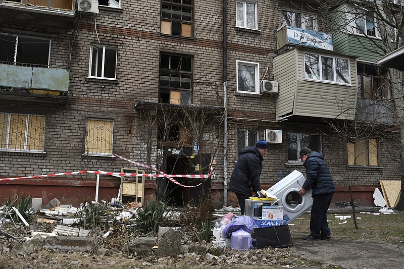 Local residents carry their belongings as they leave their home damaged in the night Russian rocket attack in Zaporizhzhya, Ukraine, Monday, Jan. 16, 2023. (AP Photo/Andriy Andriyenko)