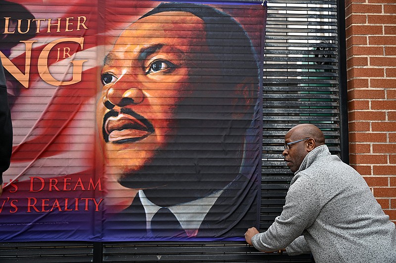 Keith Robertson, from Des Arc, helps hang a flag honoring Martin Luther King before the start of a food giveaway to celebrate the 30th anniversary of the Martin Luther King, Jr. Commission in Little Rock on Monday, Jan. 16, 2023.

(Arkansas Democrat-Gazette/Stephen Swofford)