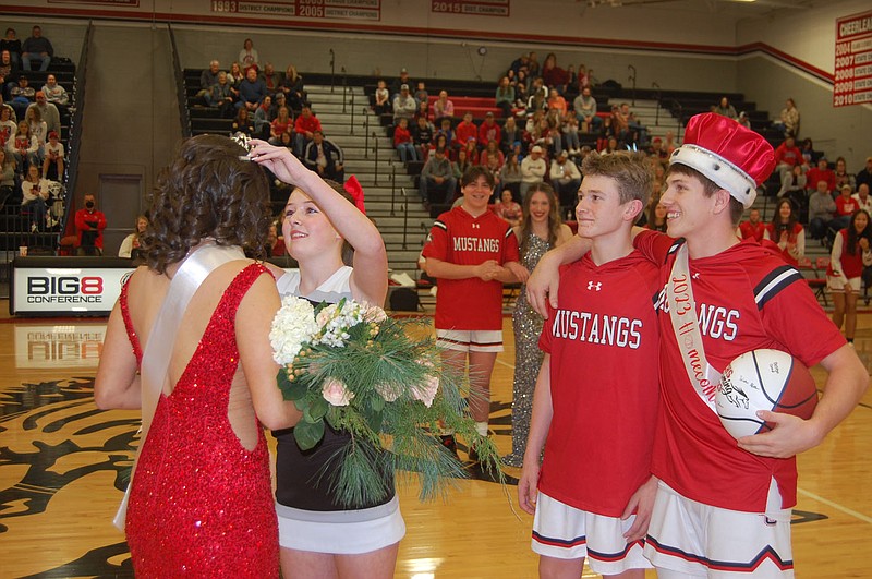 Bennett Horne/McDonald County Press McDonald County senior cheerleader Abigail Pagel places the crown on Homecoming Queen Analisa Ramirez while Wyatt Gordon and Homecoming King Cross Dowd look on during the Homecoming ceremony held Friday, Jan. 13, at Mustang Arena.