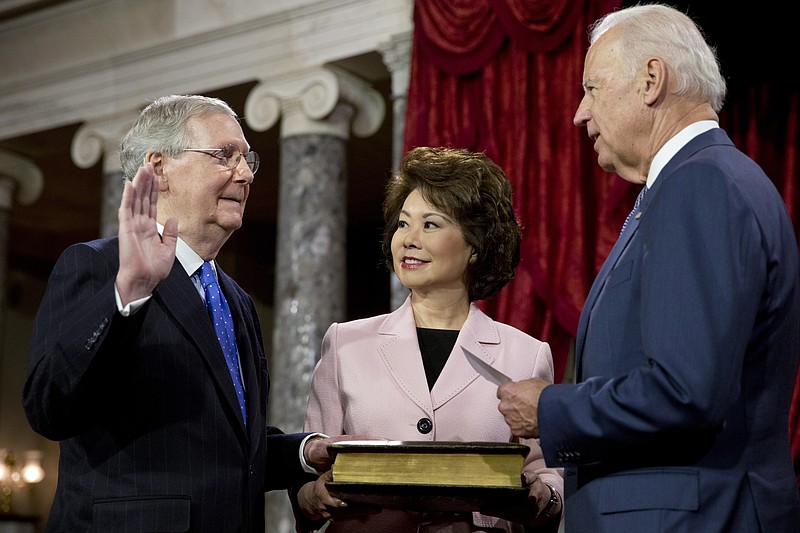 FILE - Vice President Joe Biden, right, administers the Senate oath to incoming Senate Majority Leader Mitch McConnell of Ky., with McConnell's wife, former Labor Secretary Elaine Chao, center, during a ceremonial re-enactment swearing-in ceremony, Jan. 6, 2015, in the Old Senate Chamber of Capitol Hill in Washington. By temperament and manner, Joe Biden and Mitch McConnell are decidedly mismatched. But as the days of divided government under Biden begin, their long relationship will become even more vital. McConnell&#x2019;s experience in cutting deals and the political capital he retains among his members could leave him much freer to negotiate thorny matters with the White House.  (AP Photo/Jacquelyn Martin File)