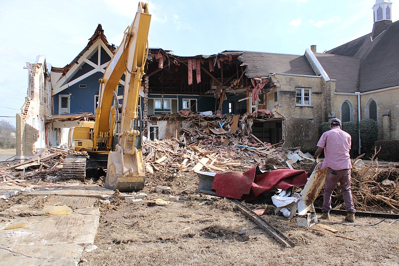 Timothy Finley works to remove debris from the yard at the old Immanuel Baptist Church building, where One Community Church is now located, on Jan. 11, 2023. The "old education wing" of the building is being demolished due to structural issues. (Caitlan Butler/News-Times)