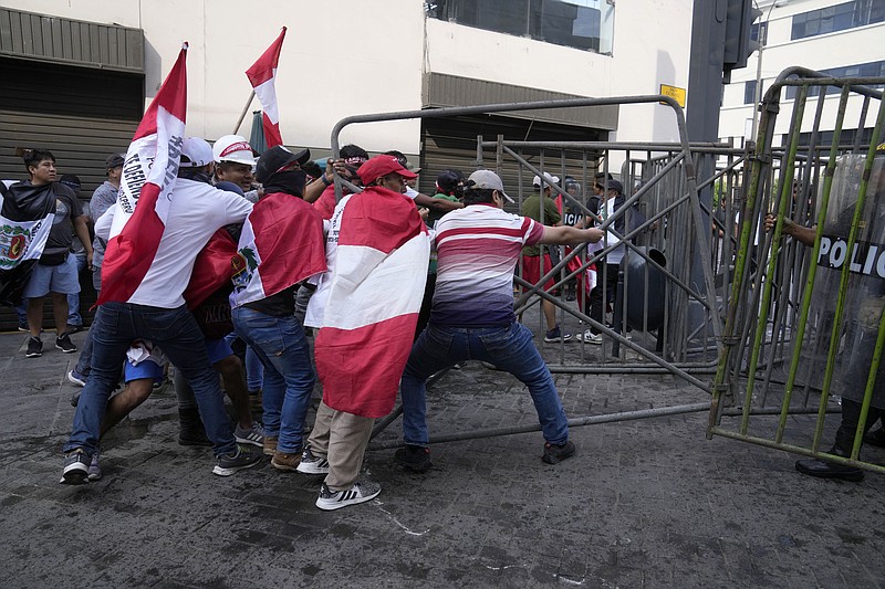 Anti-government protesters who traveled to the capital from across the country to march against Peruvian President Dina Boluarte, tear down a police barricade during clashes in Lima, Peru, Thursday, Jan. 19, 2023. Protesters are seeking immediate elections, Boluarte's resignation, the release of ousted President Pedro Castillo and justice for up to 48 protesters killed in clashes with police. (AP Photo/Martin Mejia)
