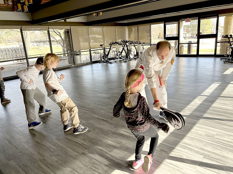 Rachel Dickerson/The Weekly Vista Karate instructor Robert White holds a target for a student to practice a kick while other students also practice their kicks during a kids' karate class at Metfield Clubhouse on Jan. 21.