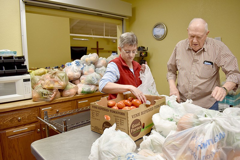 McDonald County Press/Rachel Dickerson
Debbie Ray (left) and Warren Henderson bag up tomatoes for those who were to receive food at Oasis Food Pantry on Jan. 18. Behind them (center, left) and in front of them (bottom, right) are stacks of bags of fresh vegetables and fruits. Ray has been volunteering with the food pantry for two and a half years, while Henderson has been a volunteer there for four years.