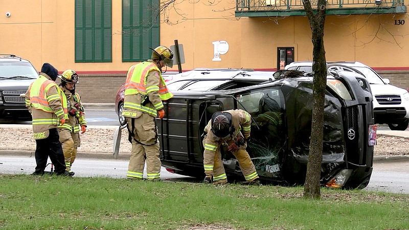 Hot Springs firefighters work the scene of a single-vehicle rollover wreck in the 100 block of East Grand Avenue Tuesday morning. - Photo by Lance Porter of The Sentinel-Record