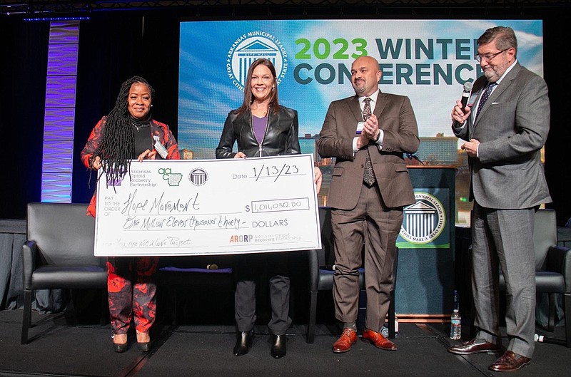 From left, Tenesha Barnes, deputy director of Arkansas Opioid Recovery Partnership; Staci James, executive director of Hope Movement Coalition; Kirk Lane, director of ARORP; and Mark Hayes, executive director of the Arkansas Municipal League, pose with a check representing $1 million in opioid settlement funds awarded James' organization. (Submitted photo)