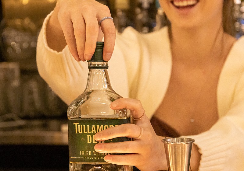 Josh Cobb/News Tribune photo: A bartender uncorks a bottle of Irish Whiskey for customers at Barvino, a full service wine bar that also serves craft beers and whiskey.