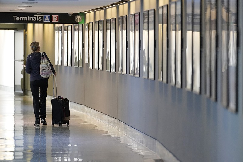 A traveler pulls their luggage between terminals Wednesday, Jan. 11, 2023, at Logan International Airport in Boston. Airline and hotel elite status extensions due to the COVID-19 pandemic are expiring this year, and the companies are raising the requirements to earn status. (AP Photo/Steven Senne, File)