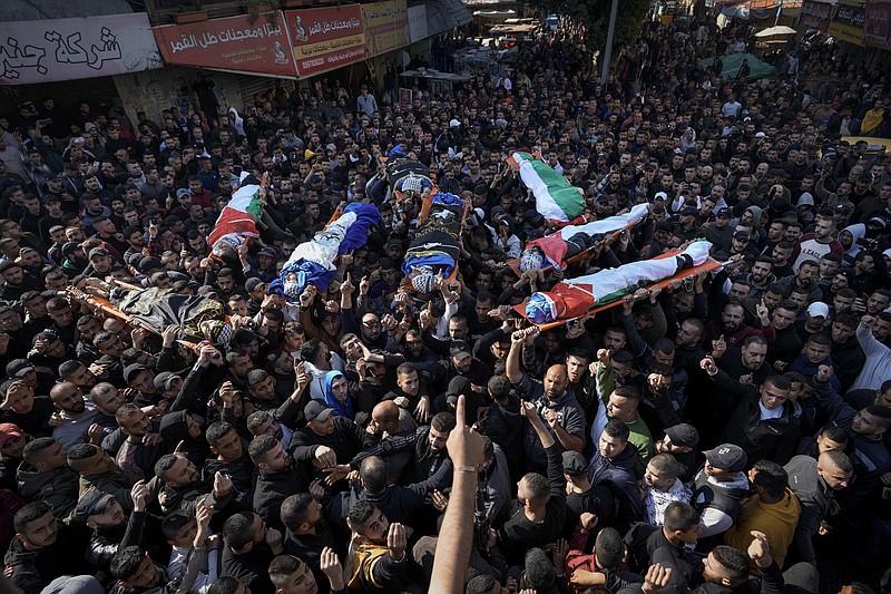 Mourners carry the bodies of eight Palestinians, some draped in the flag of the Islamic Jihad militant group, during a joint funeral in the West Bank city of Jenin, Thursday, Jan. 26, 2023. Israeli forces killed at least nine Palestinians, including a 60-year-old woman, and wounded several others during a raid in the flashpoint area of the occupied West Bank, Palestinian health officials said, in one of the deadliest days of fighting in years. The Israeli military said it was conducting an operation to arrest militants when a gun battle erupted. (AP Photo/Majdi Mohammed)