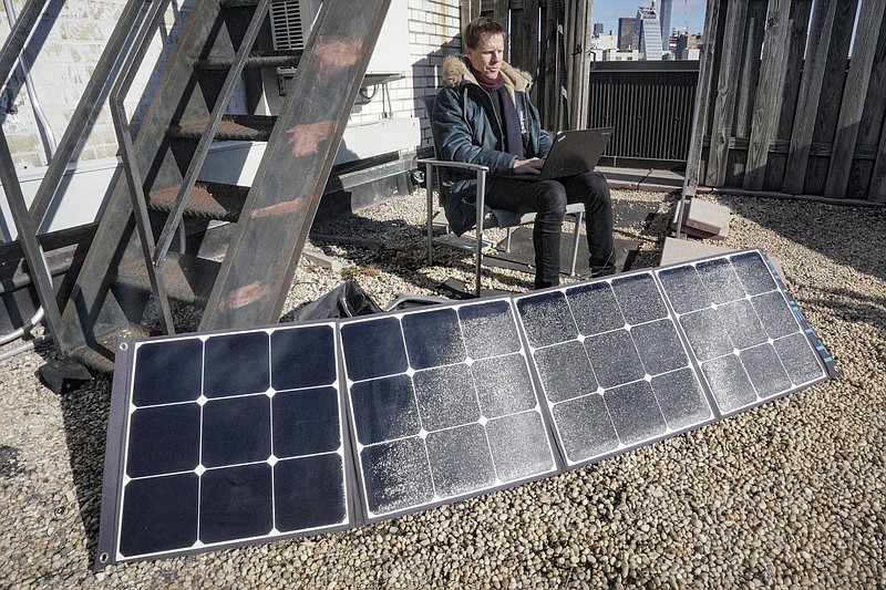 Josh Spodek works on his laptop getting charged from a portable solar kit. Spodek efforts to go packaging-free changed his mindset and led him to reduce his electrical consumption to near zero. "I want to show people this is possible, that this is desirable, that we'd only wish we had done it earlier." (AP/Bebeto Matthews)