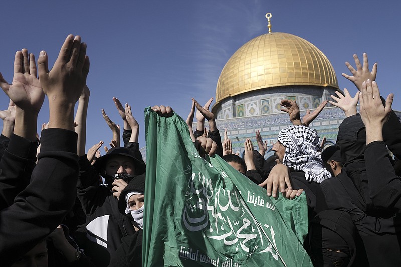 Palestinians holding a Hamas flag, protest by the Dome of the Rock Mosque at the Al-Aqsa Mosque compound in the Old City of Jerusalem, Friday, Jan. 27, 2023.  The protest was a day after the deadliest Israeli raid in decades and raised the prospect of a major flare-up in fighting. (AP Photo/Mahmoud Illean)
