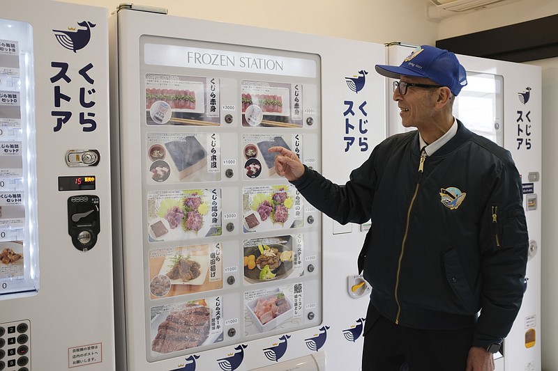 CORRECTS THE PHOTOGRAPHER'S NAME TO KWIYEON HA - Konomu Kubo, a spokesperson for Kyodo Senpaku Co. explains how whale meat is being sold from a vending machine at the firm's store, Thursday, Jan. 26, 2023, in Yokohama, Japan. The Japanese whaling operator, after struggling for years to promote its controversial products, has found a new way to cultivate clientele and bolster sales: whale meat vending machines. (AP Photo/Kwiyeon Ha)