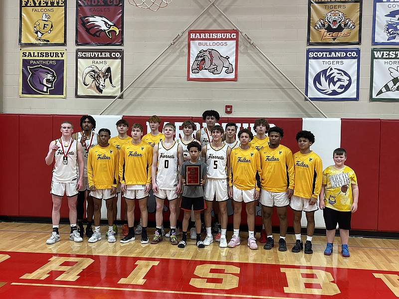 The Fulton Hornets boys basketball team poses for a photo with the Harrisburg Tournament championship plaque after beating Blair Oaks Saturday night at Harrisburg High School. Walker Gohring, Donovan Weigel and Colby Lancaster made the all-tournament team for Fulton. (Fulton Sun/Robby Campbell)