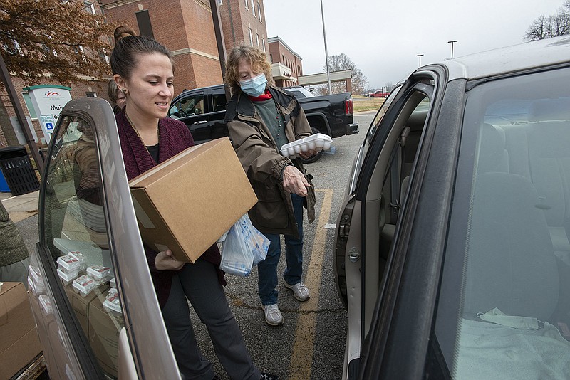 Amber Smith (left) and T.A. Sampson load food Dec. 7 into a veteran' car at Veterans Health Care System of the Ozarks in Fayetteville. Benton County Veteran Services recently established a food collection box to help the Veterans Health Care System of the Ozarks in Fayetteville. Visit nwaonline.com/photo for today's photo gallery.   (File Photo/NWA Democrat-Gazette/J.T. Wampler)