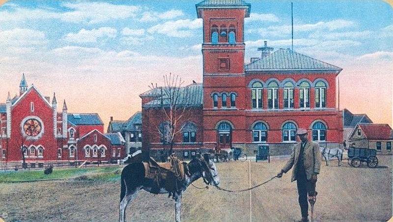 George Strong is seen with a donkey in an undated photo taken in downtown Texarkana in front of the post office, which became the site of the present-day federal building. The photo was incorporated in the iconic postcard "Man in Arkansas and His Ass in Texas." Texarkana Museums System will host a living history performance of Strong's life Saturday, Feb. 18, 2023, at the site where the photo was taken. The presentation is part of Texarkana's year-long sesquicentennial celebration. (Photo courtesy Texarkana Museums System)