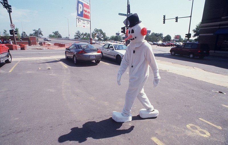 Samuel Murphy, wearing a Frosty the Snowman suit for an ad shoot June 10, 1999, at Markham and Scott streets in Little Rock, walks back to the Studio C offices when it was finished.  (Democrat-Gazette file photo)
