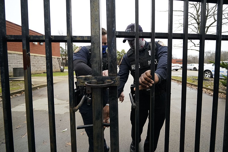 Memphis police lock a gate at a precinct as a group of demonstrators approach to protest the death of Tyre Nichols, who died after being beaten by Memphis police officers, in Memphis, Tenn., Sunday, Jan. 29, 2023. (AP Photo/Gerald Herbert)