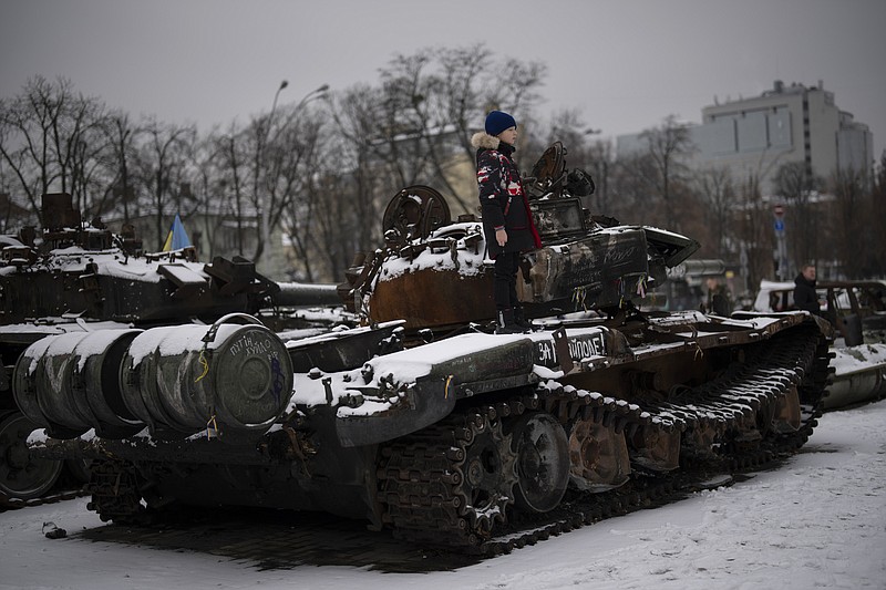 A boy stands on a destroyed Russian tank displayed in downtown Kyiv, Ukraine, Tuesday Jan. 31, 2023. (AP Photo/Daniel Cole)