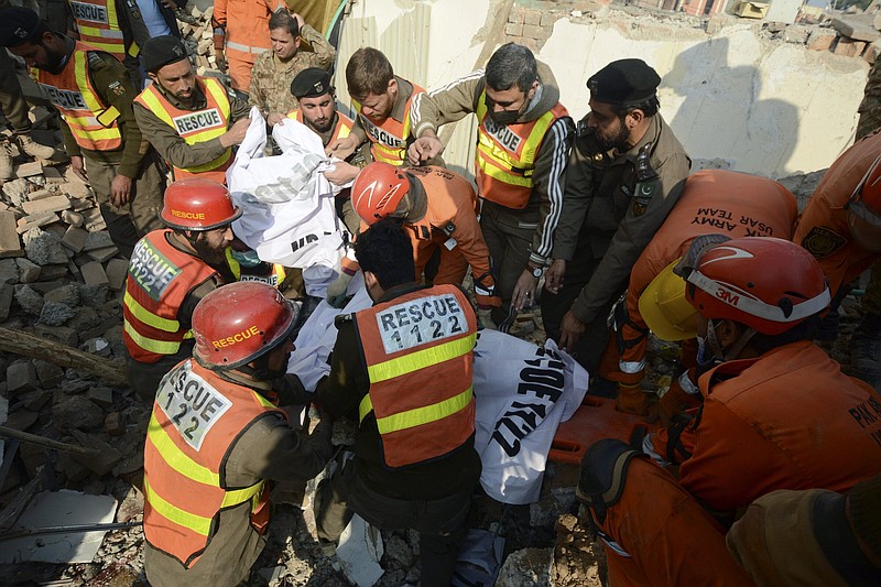 Rescue workers cover the remains of a body after being recovered from the rubble at the site of Monday's suicide bombing, in Peshawar, Pakistan, Tuesday, Jan. 31, 2023. The death toll from the previous day's suicide bombing at a mosque in northwestern Pakistani rose to more than 85 on Tuesday, officials said. The assault on a Sunni Mosque inside a major police facility was one of the deadliest attacks on Pakistani security forces in recent years. (AP Photo/Muhammad Zubair)