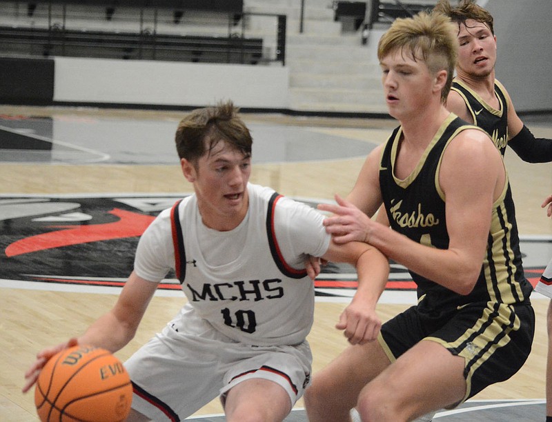 Bennett Horne/McDonald County Press McDonald County senior guard Sterling Woods (10) drives against a Neosho defender during their December matchup at Pea Ridge, Ark. Woods and the Mustangs return to the court Friday at East Newton.