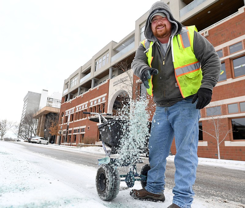 Travis Bowden, a longtime worker with the Fayetteville Parks and Recreation Department, spreads salt Wednesday to remove ice from a sidewalk on the square in downtown Fayetteville. Crews spent the morning clearing ice and snow from sidewalks and streets after more wintry weather. Visit nwaonline.com/photo for today’s photo gallery.

(NWA Democrat-Gazette/Andy Shupe)