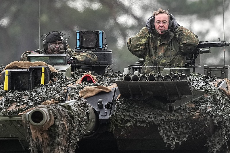 German Defense Minister Boris Pistorius, right, sits on a Leopard 2 tank at the Bundeswehr tank battalion 203 at the Field Marshal Rommel Barracks on Wednesday, Feb. 1, 2023, in Augustdorf, Germany. After the government's decision to deliver fourteen Leopard 2 tanks to Ukraine, the capabilities of the Leopard 2A6 main battle tank are shown at a presentation in Augustdorf. (AP Photo/Martin Meissner)
