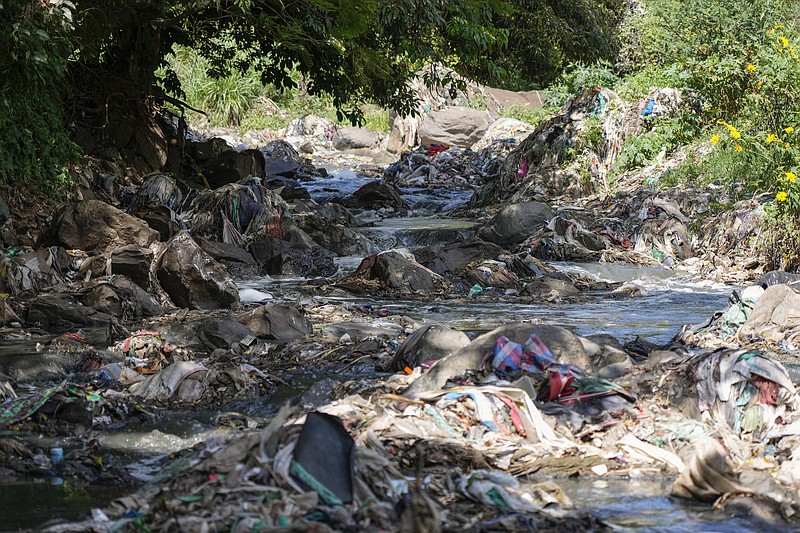 Un afluente del río Nairobi, que pasa por asentamientos informales y centros industriales, se desplaza en medio de la basura el 11 de enero de 2023, en Nairobi, Kenia. (AP Foto/Khalil Senosi)