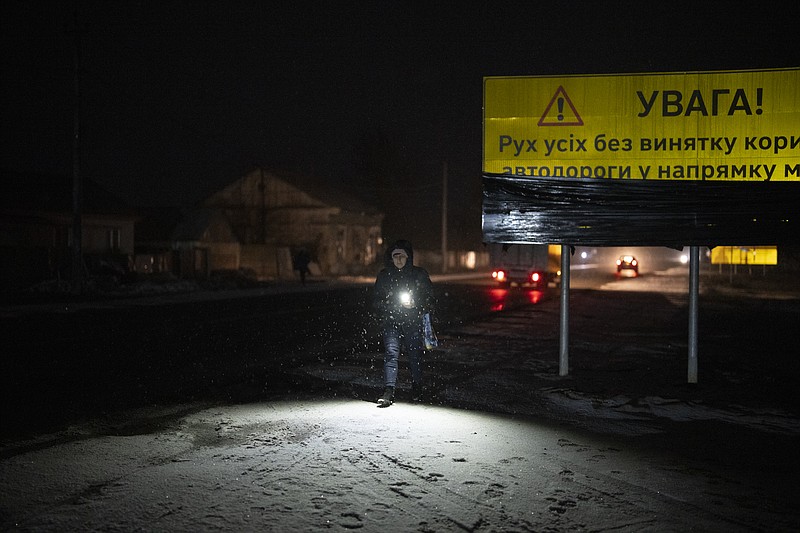Una mujer camina con una lámpara en la localidad de Kolychivka, Ucrania, el miércoles 1 de febrero de 2023. (AP Foto/Daniel Cole)