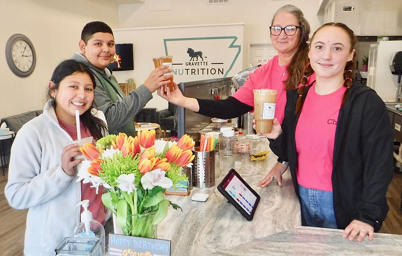 Susan Holland/Westside Eagle Observer
Alyssa Sanchez and her brother Justin Yboa smile for the camera as they pick up their drinks during Gravette Nutrition's second birthday party Friday afternoon, Feb. 3. Business owner Marisa Crain and her helper Chloe Lucas (right) prepared shakes and specialty teas for several customers who dropped in to help them celebrate. Drawings were held for several door prizes.