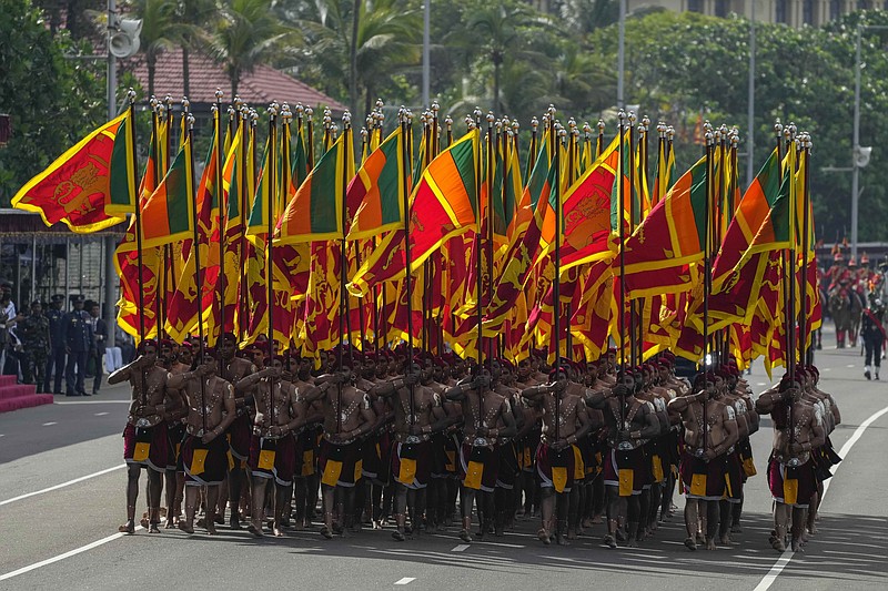 Sri Lankan army soldiers march carrying national flags during the 75th Independence Day ceremony in Colombo, Sri Lanka, Saturday, Feb. 4, 2023. Sri Lanka marks the anniversary of independence from British colonial rule on Feb. 4 each year. (AP Photo/Eranga Jayawardena)