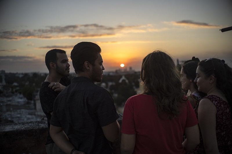 Marcos Marzo, second left, talks with his friends who came to say goodbye upon receiving the news that he obtained a permit to travel to the United States,  in Havana, Cuba, Wednesday, Jan. 25, 2023. A close relative told Marzo on Jan. 21 that he had applied online to sponsor his trip to Florida as required by the new parole program for Cuban migrants set up by the Biden administration. The next day the sponsorship had been confirmed and the day after that it was approved. (AP Photo/Ramon Espinosa)