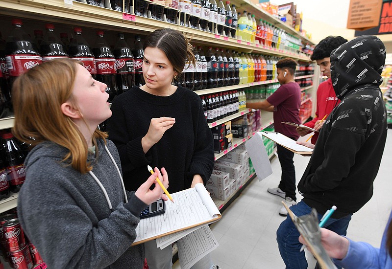 Teacher Valkyrie Holmes (center) helps Emeri Hurley (left), a sixth-grader at Holt Middle School, as she and other students do calculations Tuesday at the Harps grocery store on Wedington Drive in Fayetteville. The students, led by teacher Kacie Travis, were learning how to calculate unit prices for groceries, which allows shoppers to decide what purchase gives the best value. An eight-month study by Forward Arkansas showed there are achievement gaps among students living in different parts of the state with Northwest Arkansas students outperforming their peers in other parts of the state.
(File Photo/NWA Democrat-Gazette/Andy Shupe)
