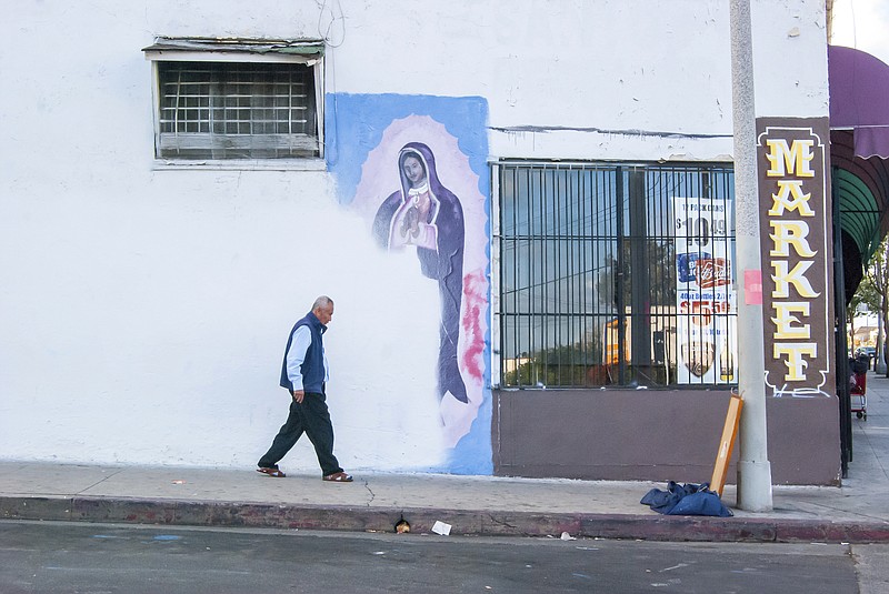 In this photo by Oscar Rodriguez Zapata, a man walks next to a partially-covered Virgin of Guadalupe mural in Los Angeles in 2018. January 2023 marked 10 years since Zapata began documenting images of Guadalupe, at first on his phone for his own pleasure, but eventually taking his hobby more seriously, particularly as he noticed more and more Guadalupe images were vanishing. (Oscar Rodriguez Zapata via AP)