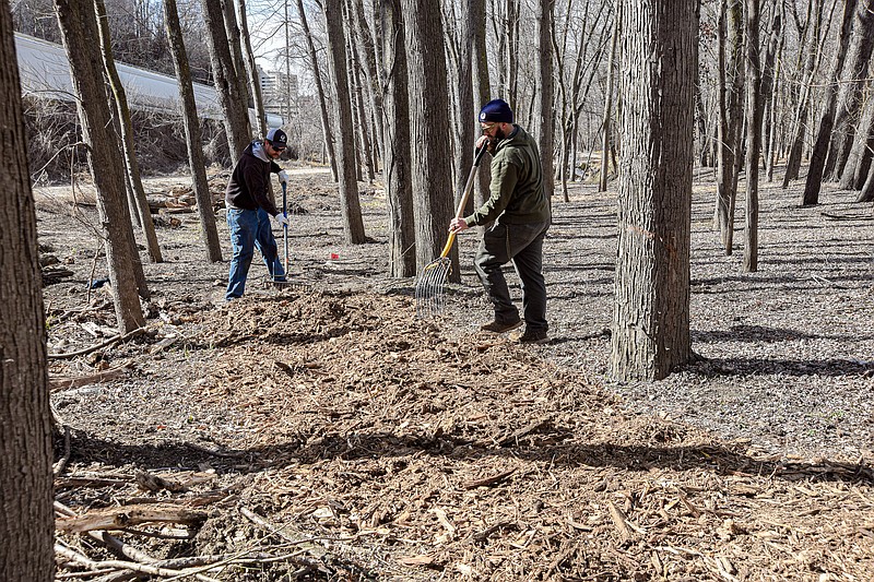 Julie Smith/News Tribune photo: 
Shawn Sachs, background left,  and Zac Baladenski spread tree mulch Tuesday, Feb. 21, 2023, on what will be Jefferson City's newest walking trails. This winding trail is at the east end of Adrian's Island and will soon be completed and measures about two-tenths of a mile. Sachs and Baladenski work for Parks and Rec and have been working on the project for a couple of days to get this section done.