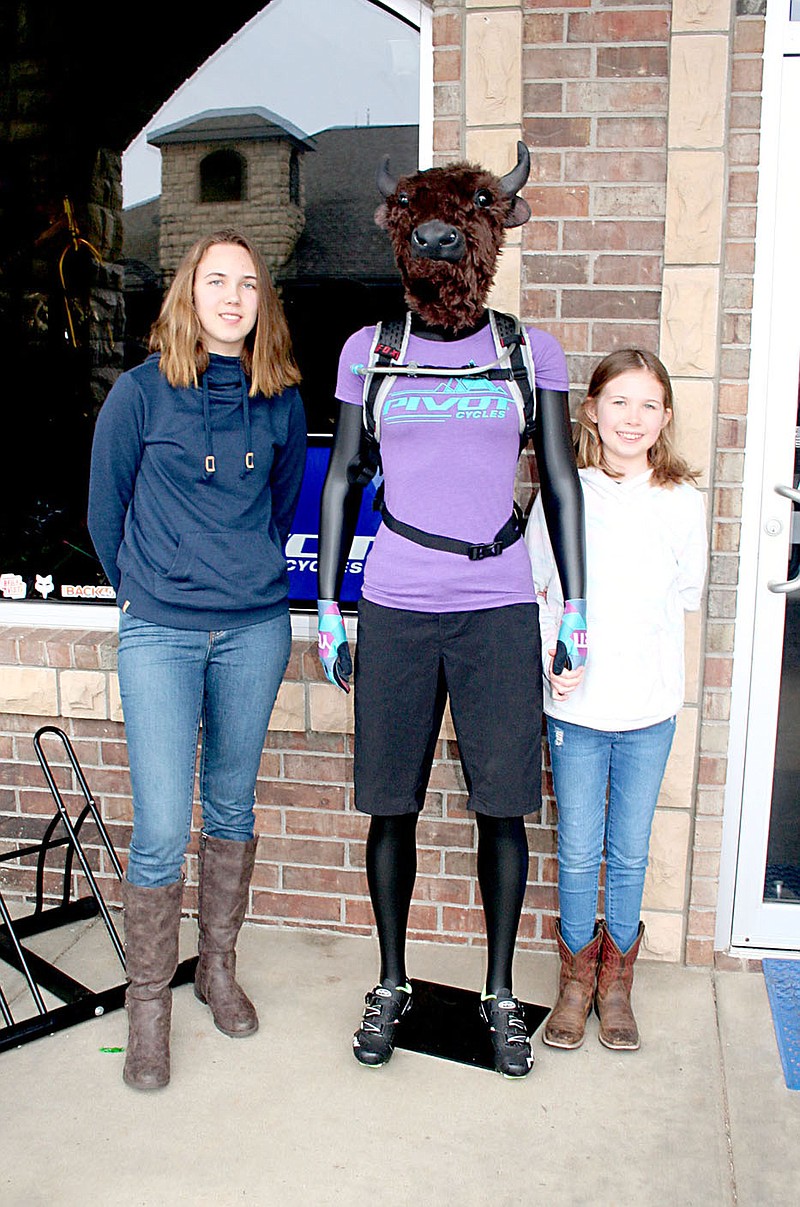 Lynn Atkins/Special to The Weekly Vista Gretchen and Elise McCann pose with the new Bison Bikes mascot during a demo day on Sunday. The name Bison Bikes is derived from shop owner Kendall McCann’s middle name, Byson, which is also his mother’s maiden name.