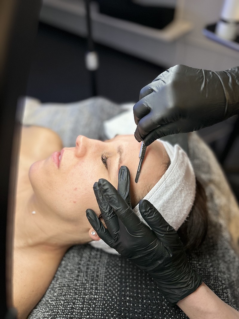 Alex Haslag dermaplanes a client's face, a process that uses a razor-like tool to remove the top layer of dead skin. (Gemma Asel/News Tribune photo)