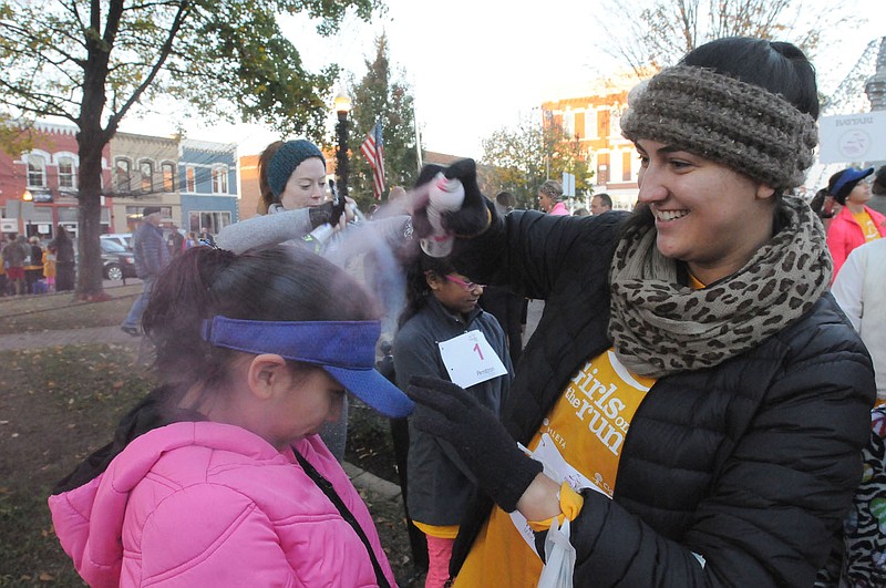 NWA Democrat-Gazette/FLIP PUTTHOFF 
READY TO RUN
Kimberly Torres, 8, gets a squirt of colored hair spray coutesy of Jessica Mounce, a teacher at Elmdale Elementary in Springdale, before Kimberly took part Saturday Nov. 12 2016 in the Girls on the Run 5-kilometer run in downtown Bentonville. Hundreds of girls on school teams in Northwest Arkanas took part in pre-run festivities and the 3.1-mile run. Girls on the Run is a national program that encourages pre-teen girls to develop self-respect and a healthy lifestyle through class work and physical activity. The program's finale is a celebratory run.