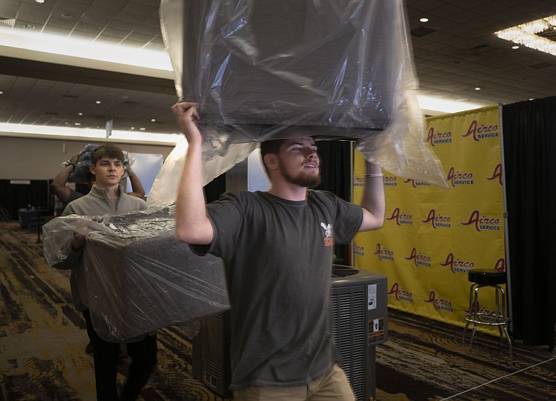 Bentonville Ignite students and volunteers Jacob Hillis (from left) and Ethan Chaplain carry couch cushions for the Jack Wills Outdoor Living display, Thursday, March 2, 2023 at the Northwest Arkansas Convention Center in Springdale. The Convention Center will host the 33rd annual NWA Home Show featuring 110 vendors each specializing in a variety of home improvement projects from small home projects to new home construction and everything in between. The show will run from Friday to Sunday. People can buy tickets at the door or ahead of time at nwahomeshow.com. Visit nwaonline.com/photos for today's photo gallery.

(NWA Democrat-Gazette/Charlie Kaijo)