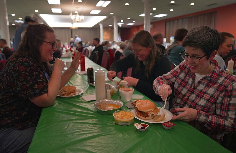 From left, Laura Kuster, Miranda Crotsley, and Hollen Barmer eat fish sandwiches, homemade perogies, and macaroni and cheese at the St. Maximilian Kolbe Catholic Church fish fry in the West Homestead neighborhood of Pittsburgh, on Friday, Feb. 24, 2023. To innovate the age-old tradition of fish fries, Barmer and volunteers from Code for Pittsburgh created the &quot;Pittsburgh Lenten Fish Fry Map,&quot; an online interactive map that locates and documents active fish fries from year to year across Western Pennsylvania. (AP Photo/Jessie Wardarski)