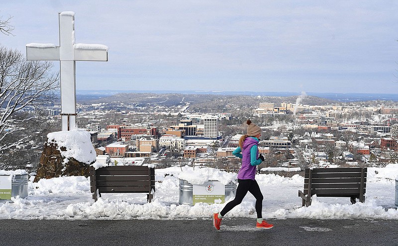 A runner passes the cross and the scenic overlook Thursday, Jan. 26, 2023, on Skyline Drive on Mount Sequoyah in Fayetteville. The popular spot overlooks downtown Fayetteville and offers a view of the University of Arkansas. Visit nwaonline.com/photo for today's photo gallery. 
(NWA Democrat-Gazette/Andy Shupe)