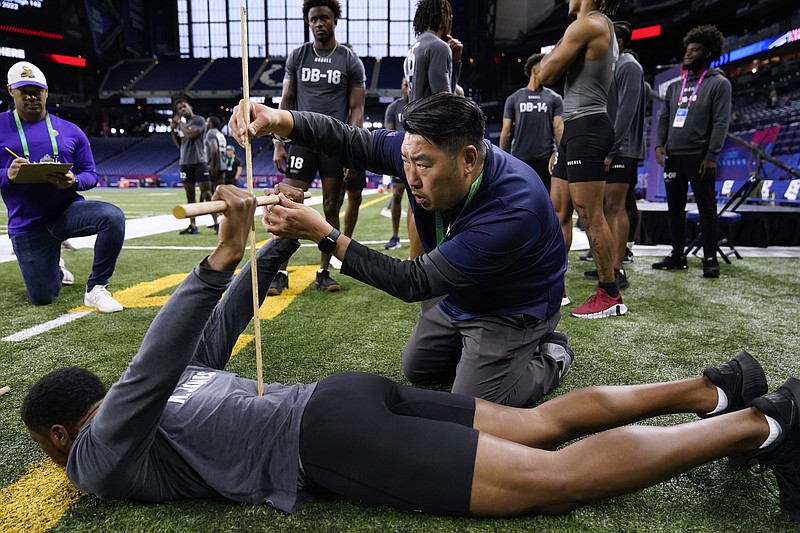 Denver Broncos scout Sae Woon Jo measures the flexiblity of Ball State defensive back Nic Jones at the NFL football scouting combine Friday, March 3, 2023, in Indianapolis. (AP Photo Erin Hooley)