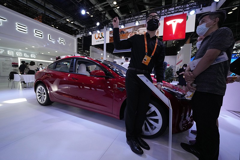 A staff member chats with visitors to the Tesla booth during the China International Fair for Trade in Services (CIFTIS) in Beijing, Thursday, Sept. 1, 2022. (AP Photo/Ng Han Guan)