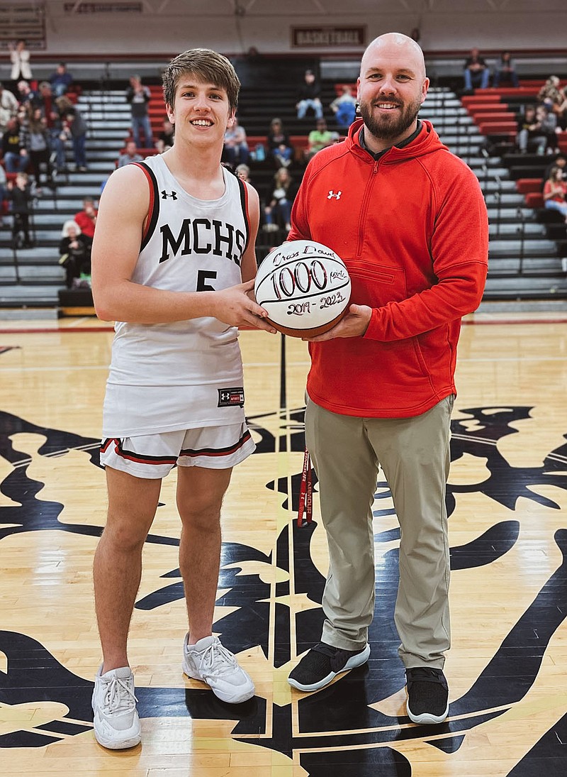Submitted photo McDonald County athletics director Bo Bergen presents a basketball to Cross Dowd commemorating the Mustang senior’s achievement of surpassing the career 1,000-point mark. Dowd finished his high school basketball career with 1,031 points. The ceremony took place prior to McDonald County’s game against Willow Springs on Tuesday, Feb. 21, at Mustang Arena.